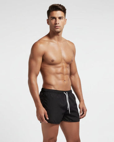 Man wearing black swim shorts on a white background