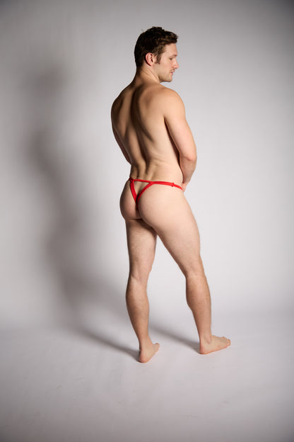 Man wearing a red thong against a gray background