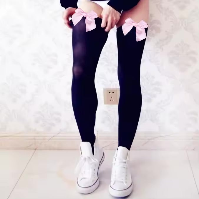 Black tights with pink bows worn by a person, standing on a light-colored floor.