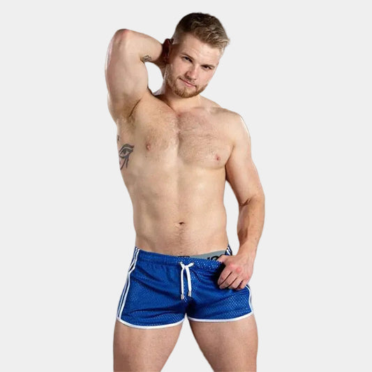 Man wearing blue swim shorts against a dark background